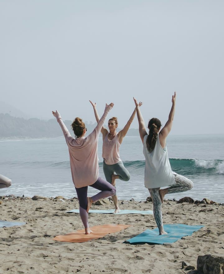 Grupo praticando yoga na praia ao amanhecer